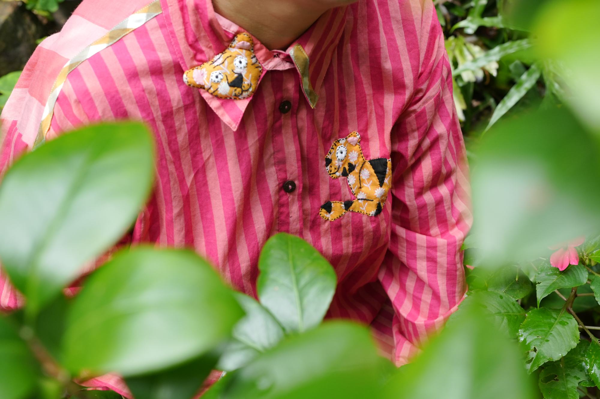 A pink striped shirt with hand-appliquéd folk-art tigers on the collar and pocket