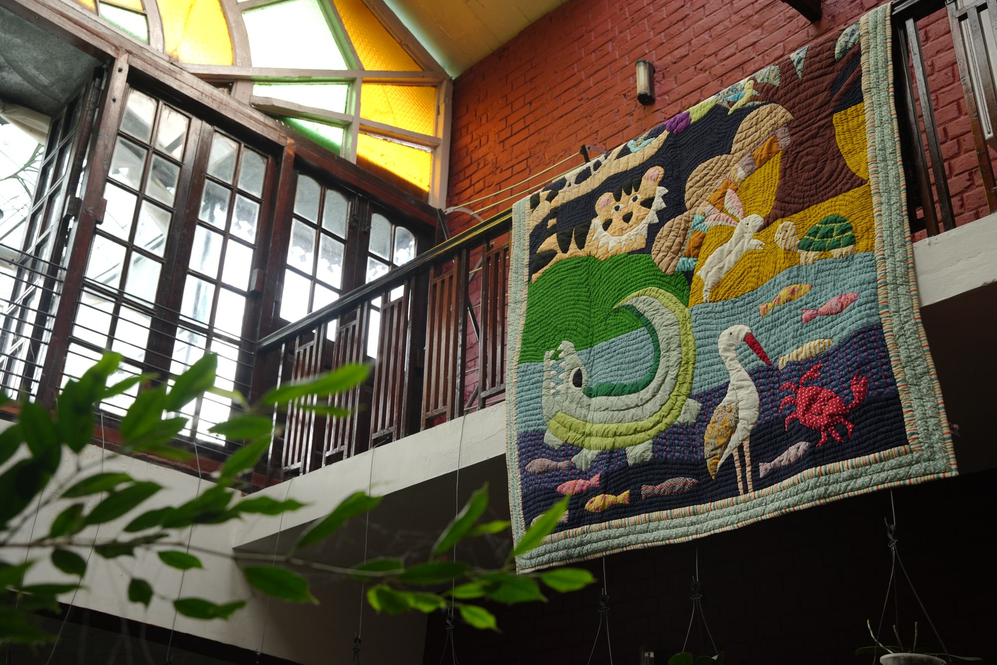 An appliquéd art quilt of animals hung over a railing in a brick stairwell