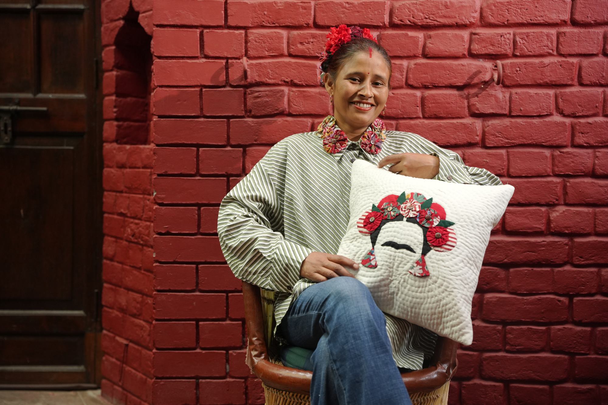 A Purkal Didi holding a cushion appliquéd with Frida Kahlo in a crown of yo-yo flowers