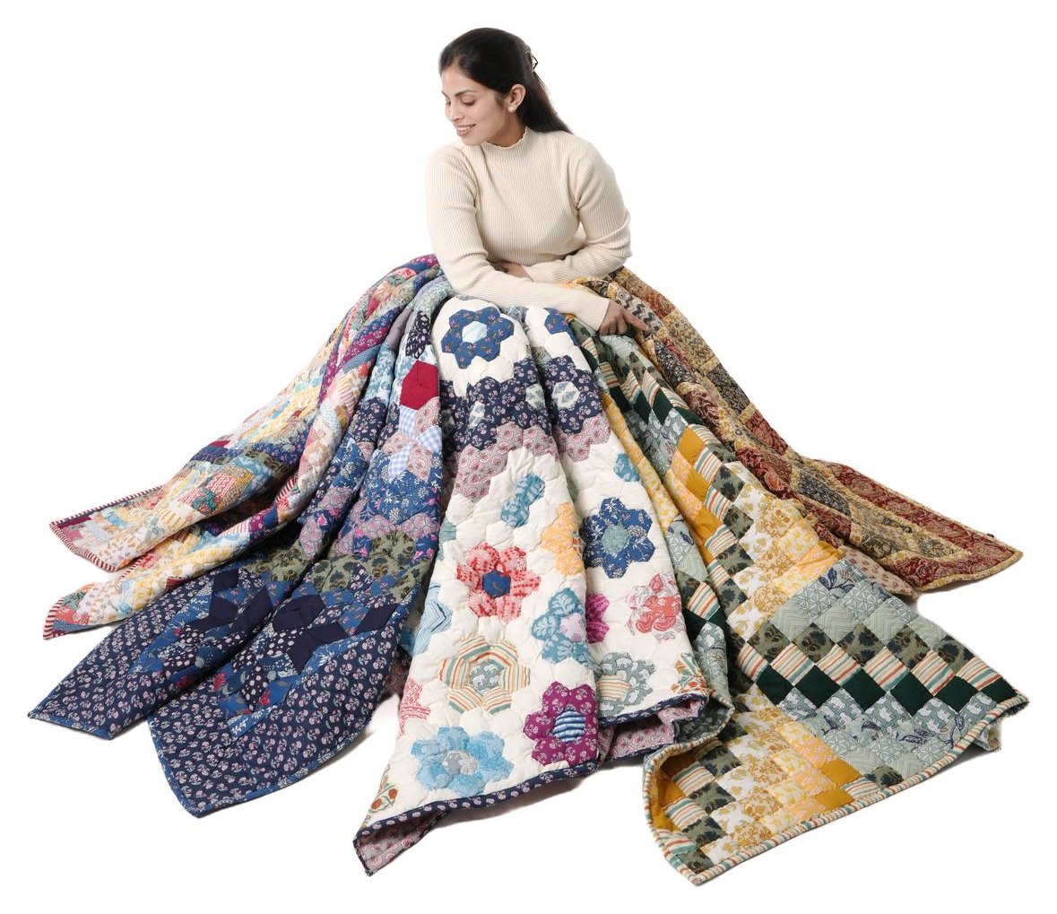 A woman holding an armful of finished Purkal quilts