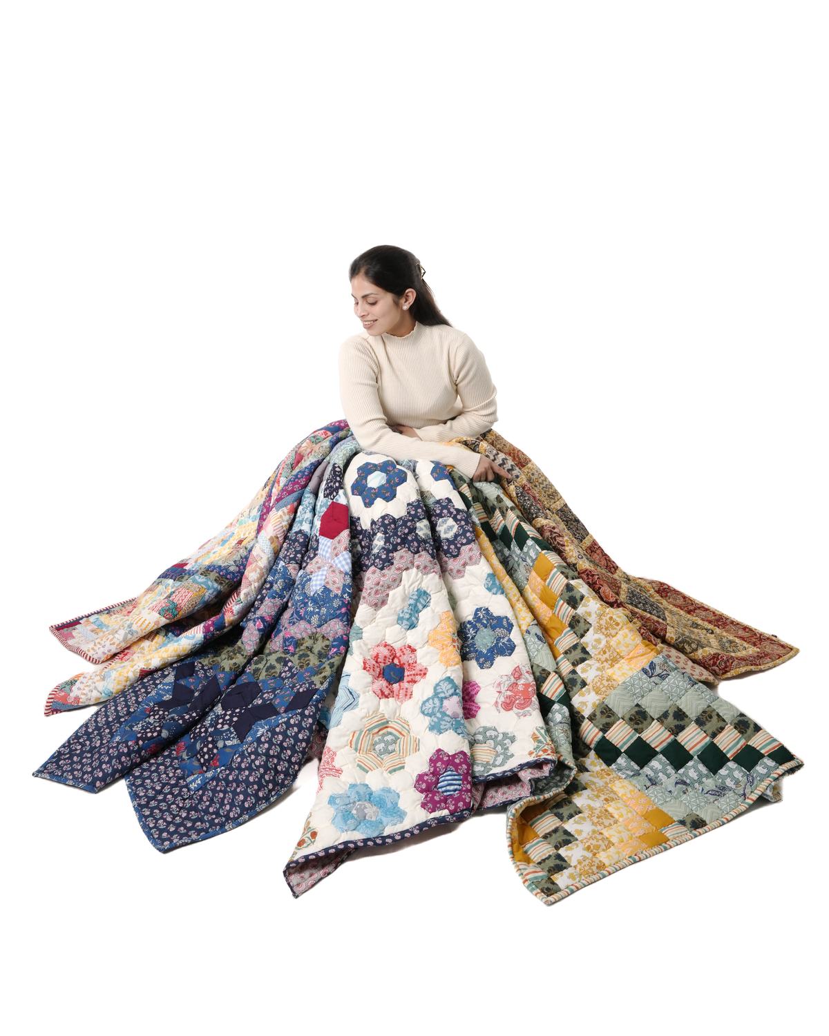 A woman holding an armful of finished Purkal quilts